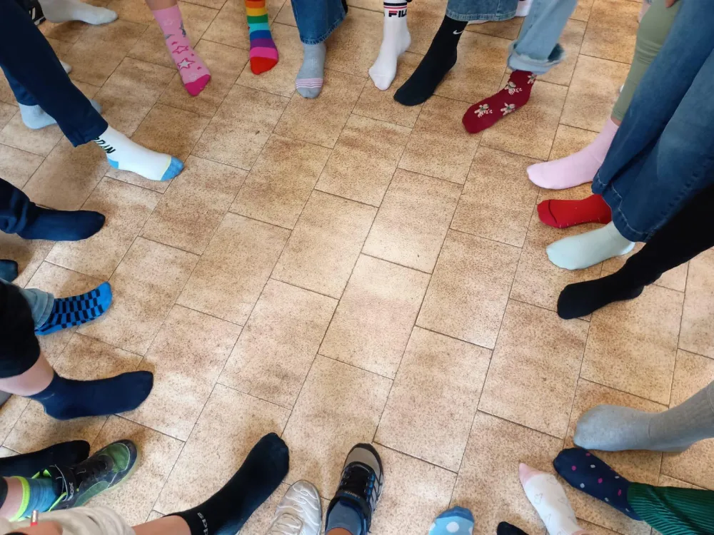 Piedi in cerchio su un pavimento di piastrelle, ognuno con due calzini diversi.